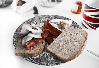 Close-up of blue plate with british breakfast. Bacon with fried egg, with sprinkles of pepper on sliced wholemeal bread. 