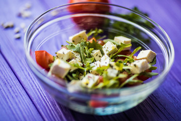 Fresh Greek salad in a bowl, top view on wooden table