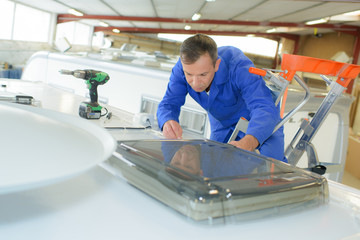 Mechanic working on roof of camper van - obrazy, fototapety, plakaty