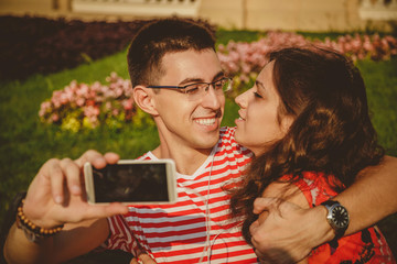 Happy beautiful couple taking selfie on mobile phone, hugging and having fun together