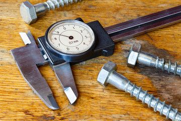 Slide caliper with a round dial on the table in workshop
