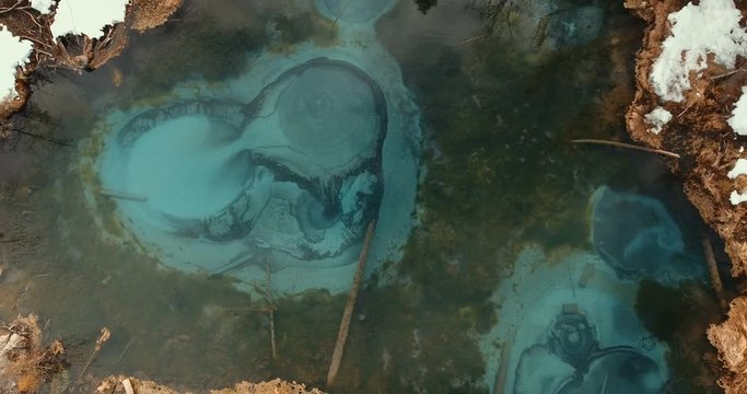 The magic miracle of nature is a geyser lake. Amazing view from above on a geyser lake of azure color. Unfreezing thermal spring - a geyser lake fancifully changes the pattern on the water surface.