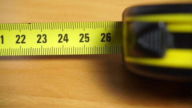 Tape measure on the brown wooden background.  Construction, engineering, repair concept. Dolly sliding shot 4K ProRes HQ codec