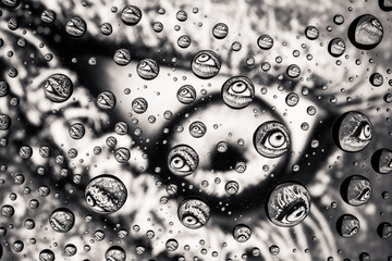 Eye close-up through drops of water on glass

