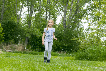 Little girl  playing with poplar fluff on the green park outdoor.