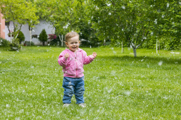 Little baby girl  playing with poplar fluff on the green park outdoor.