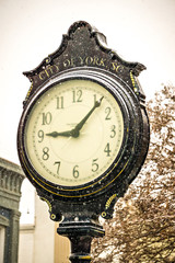 vintage historic street clock with snow falling in winter