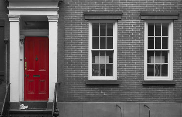 Black and white closeup of a house with red door