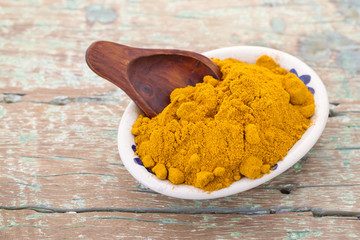 Roots and turmeric powder on wood background (long curcuma)