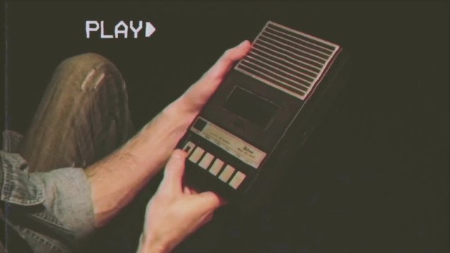 Fake VHS tape: a man inserts a tape into a cassette player and hits the record button.
