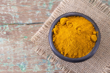 Roots and turmeric powder on wood background (long curcuma)