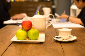 Selected focus tea cup and fresh fruit with people working