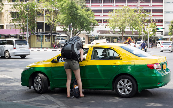 Tourist woman with backpack talking to taxi driver
