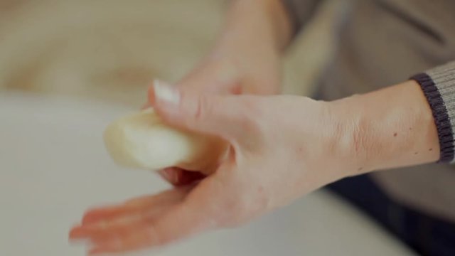 Woman kneading dough on the table.