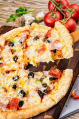 Photo of a hot pizza on wooden background.