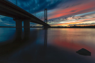 Fototapeta na wymiar Cityscape: sunset over the river against the bridge.