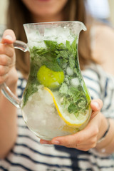 Young girl holds glass jug with fruit cocktail