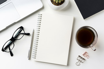 Business concept - Top view of white desktop background with notebook, coffee, smart phone, cactus and clip for mockup design