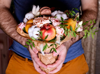 Bouquet from flowers and fruit in hands. Autumn composition