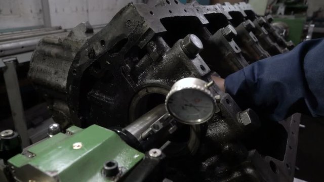 Mechanic measures the inner surface of the engine block with a micrometer. Cylinder block bore.