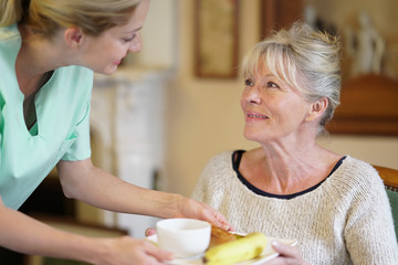 Nurse bringing breakfast to senior female patient