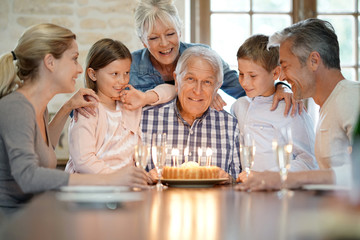 Family celebrating grandfather birthday with cake and candles
