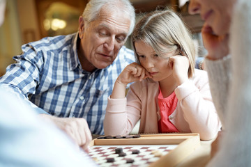 Grand-parents with grandkids playing checkers
