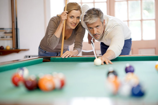 mature couple playing pool together