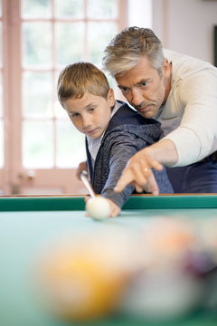 Father and son playing pool together