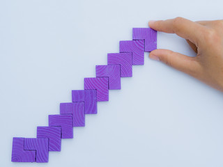 Concept of building success foundation. Women hand put puzzle wooden blocks in the shape of a staircase