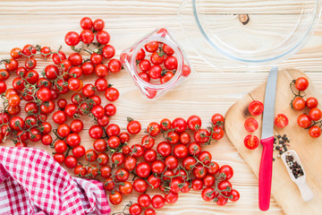 cherry tomatoes on wooden table, jar, cutting board, knife, pepper, red squared napkin, top view, - 148702109