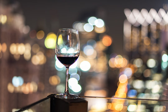 Wine glass with red wine in city bokeh background