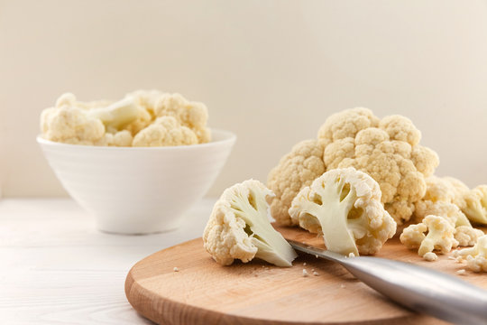 Fresh cauliflower in white dishes and on a wooden table