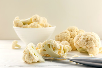 Fresh cauliflower in white dishes and on a wooden table