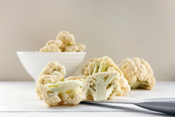 Fresh cauliflower in white dishes and on a wooden table