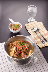 Chicken and herb soup in pot on black table background