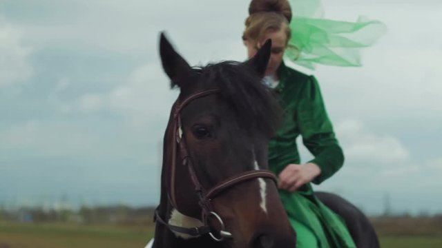 A woman in a green suit is riding a horse 4k