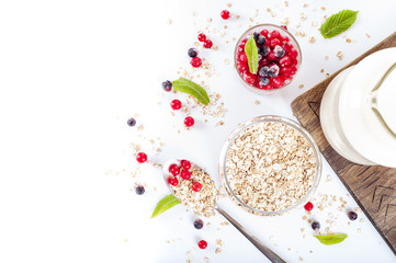 healthy breakfast: oat flakes in bowls, fresh berries and milk on white background