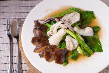 Stir fried kale with fresh squid on white dish