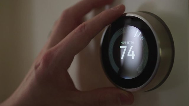 Man Adjusting Smart Thermostat Gadget At Home