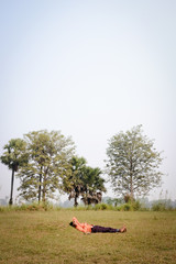Indian man sleeping on the grass in the middle of the day.