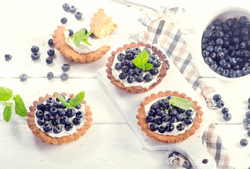 Blueberry tarts on a white wooden table.