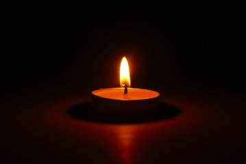 Obraz na płótnie Canvas The light of burning candle in the dark
