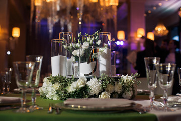 Steel forks lie beneath white plate on green dinner table