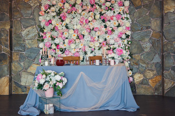 Blue dinner table stands before wall covered with flowers