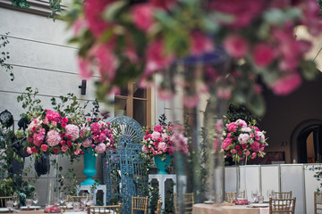 Tall vases with pink hydrangeas stand on beige tables outside