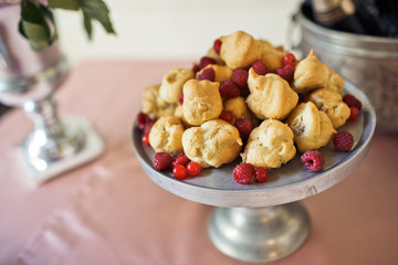 Tasty eclairs and red berries on white plate