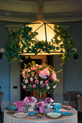 Yellow lamp hangs over dinner table decorated with pink flowers