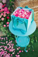 Turquois box with pink petals stands on the little table
