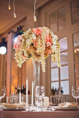 Look from below at tall vase with delicate flowers on dinner table